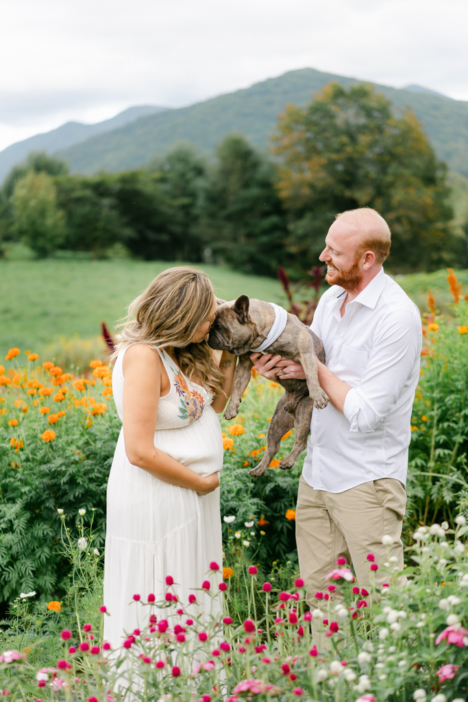 Couple with dog at their flower farm maternity session surrounded by the mountains. Photo by Asheville family photographer, Lauren Sosler Photography.