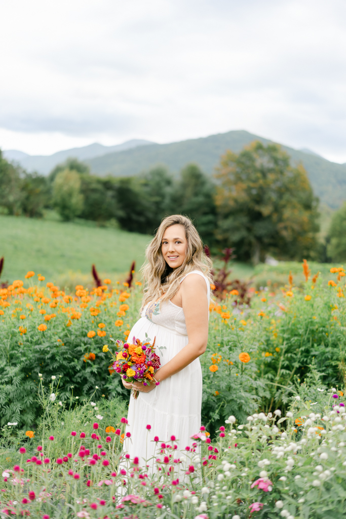 Mom with baby bump holding flowers at the never ending flower field by Asheville maternity photographer, Lauren Sosler Photography.