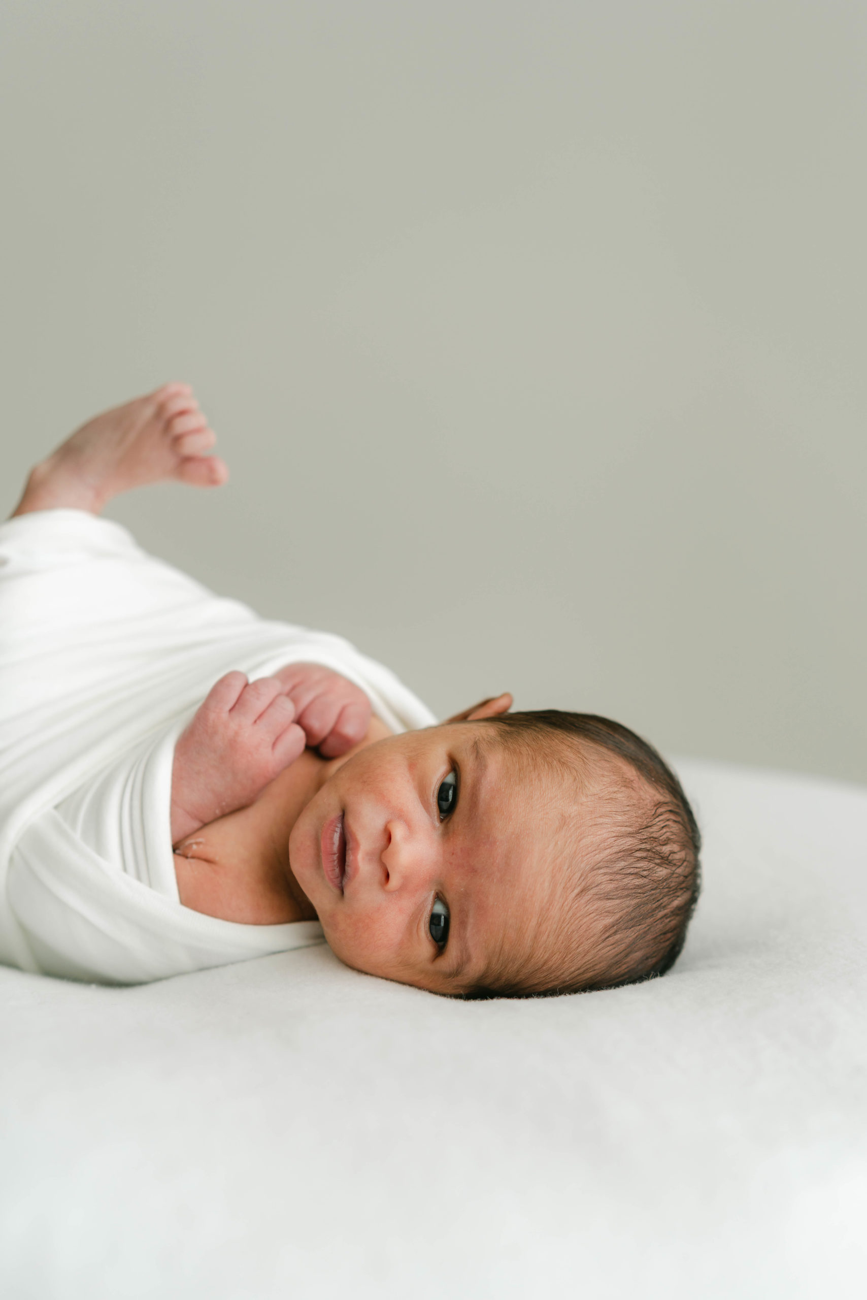 Newborn in white swaddle during lifestyle newborn session by Lauren Sosler Photography.