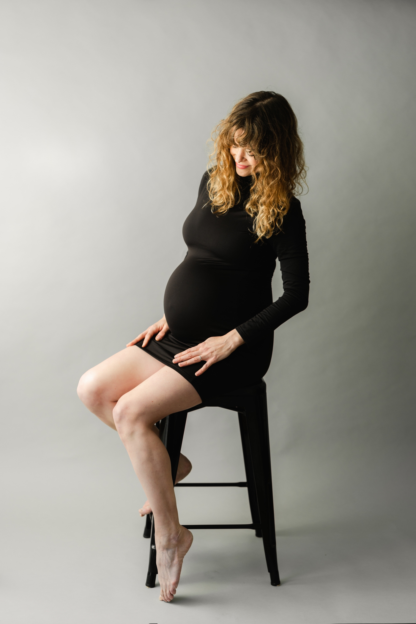 Mom wearing black form-fitting dress in studio maternity Session with Lauren Sosler Photography