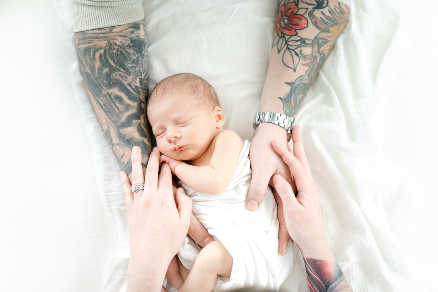 Lifestyle newborn session with baby being held by both parents. Photo by Lauren Sosler Photography.