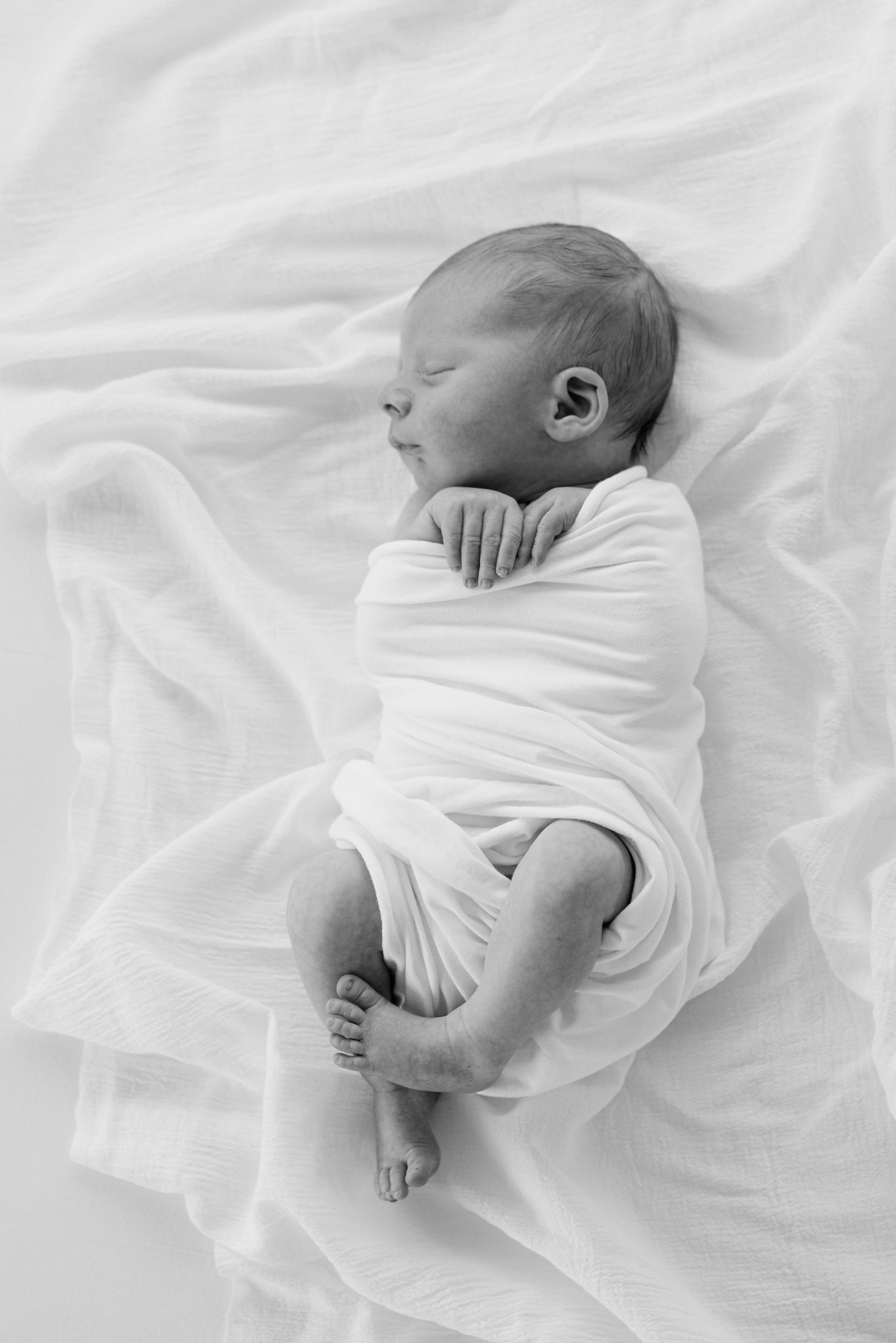 Black and white image of baby sleeping in white swaddle in Asheville NC newborn session. Photo by Lauren Sosler Photograhy.