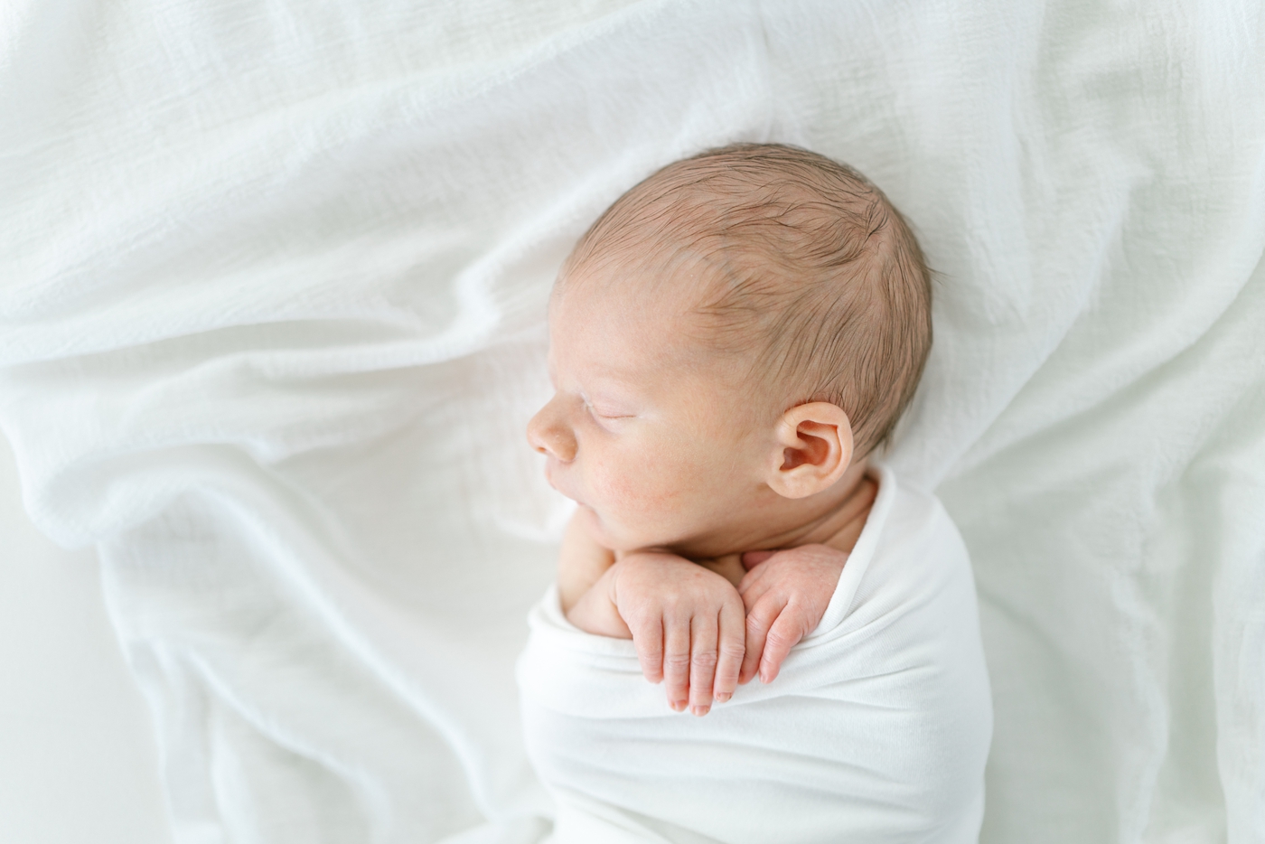 Baby sleeping in white swaddle during newborn session. Photo by Lauren Sosler Photography.