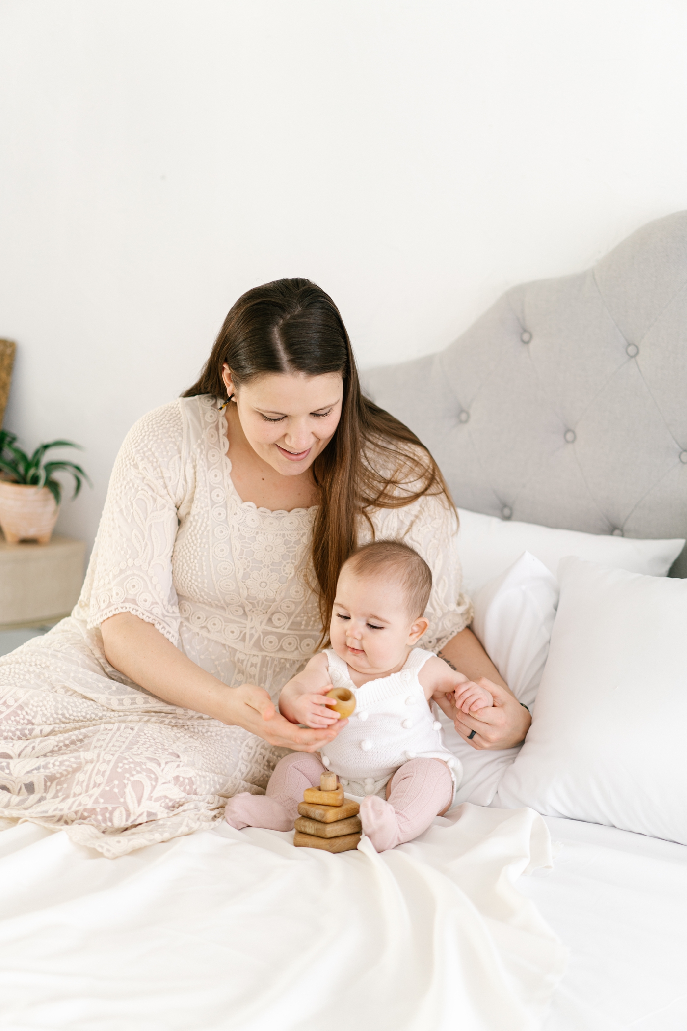 Mom sitting on bed with baby during studio motherhood and milestone session in Asheville, NC. Photo by Lauren Sosler Photography.