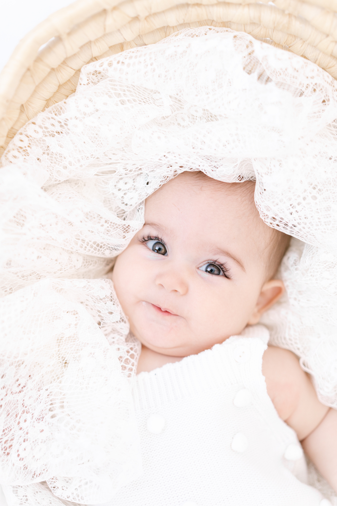 Closeup of baby in Moses basket with big brown eyes. Photo by Lauren Sosler Photography.